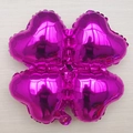 Ballon trèfle en aluminium magenta brillant sur un fond de parquet en bois clair - Rouge Rose