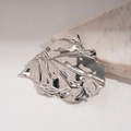 Macro-opname van metalen onregelmatige geplooide bladbroche met glanzende textuur - Zilver