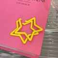 Detalle macro de pendiente de estrella amarillo brillante sobre libro rosa con perno - Amarillo