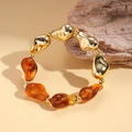 Macro-opname van onregelmatige gouden metalen en amberhars kralen op een moderne armband - Donker Koffie