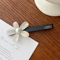 Acetate hair clip with white iridescent flower and central pearl detail on wood surface - Duckbill Hair Clips / Iridescent White