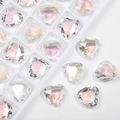 Close-up of faceted heart-shaped glass gems with iridescent shine on white background - Shimmering White