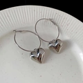 Détail de boucles d'oreilles créoles cœur argentées posées sur une assiette en céramique - 36# Tige en Argent-Pendentif Coeur Argenté (Petit)