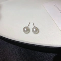 Macro view of minimalist white round pearl stud earrings with elegant silver needles - 8mm