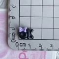 Dettaglio ciondolo 'ok' in resina nera con fiocco viola su griglia millimetrata di misura - 03*Nero Viola Fiocco OK Mini