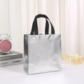 Laser film non-woven silver tote bag with black handles on a minimalist desk setting - Small (23*22*11cm) / Laser Silver