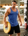 Detailed view of heather blue fitness tank top and black shorts on a gym model - Blue