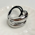 Polished silver crescent metal hair tie on a white ceramic dish with elastic band detail - Silver