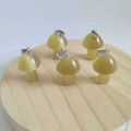 Five mini mushroom cat eye stone pendants with silver metal clasps on a wooden base - Synthetic Light Coffee Cat Eye