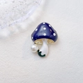 Charmante blauwe emaille paddenstoel broche met witte parel op getextureerde achtergrond - Donkerpaars