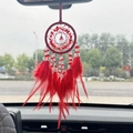 Red dream catcher car pendant with feathers and beads hanging on a rearview mirror - Red