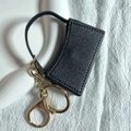 Dettaglio portachiavi porta rossetto in pelle nera con catena e chiusura dorata - Nero