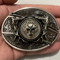 Detailed macro view of silver skull belt buckle with intricate flame and punk relief - Spinning Ghost Head
