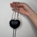Dettaglio di una mini borsa nera a forma di cuore con elegante catena in metallo - Nero