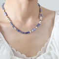 Handgemaakte kralenketting met blauwe natuursteenbuisjes en witte parels bij model - Blauwe Chalcedoon Parelketting