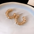 Detailed top view of golden C-shaped hoop earrings with hammered texture on white ceramic - Gold Hammered Wave C-Shape