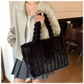 Detail of black plush tote bag featuring a unique fluffy ball handle and embossed texture - Black