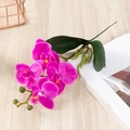 Roze paarse kunstorchidee met groene bladeren op een lichte houten tafel - 4-Kops Orchidee / Paars