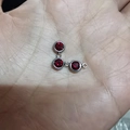 Three round red birthstone pendants in silver stainless steel finish held in a hand - Red Stone Silver Base