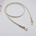 Detail of cream white PU leather strap with golden lobster clasps and metal coil detail - Beige + Gold Hook