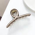 Detail view of a beige shark hair claw with dark brown stripes and metal spring mechanism - B