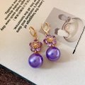 Elegante lila Blumenperlenohrringe mit Gold-Finish auf Vintage-Magazin-Hintergrund - Kristallblume mit lila Perle (38#)