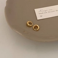 Dettaglio macro di orecchini a cerchio dorati lucidi su un piatto in ceramica beige chiaro - Oro 10mm (Mini)