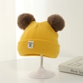 Close-up of yellow knit baby beanie with brown pom-poms and Moonlight woven label - 3-24 Months (45-50CM) / Yellow
