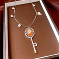 Detail eines Vintage Schlüsselanhängers mit orangem Edelstein auf roter Seide - Halskette - Silber