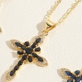 Macro detail of golden cross pendant featuring black marquise stones and white diamonds - Black Cross (Gold)
