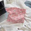 Pink floral embossed makeup bag styled with vanity accessories on a soft white bed - Flower Yellow Rabbit
