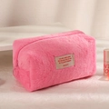 Close-up of a soft pink plush cosmetic bag with a decorative embroidered fabric label - Rose Red