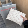 Nahaufnahme der weißen gesteppten Kosmetiktasche mit roter Hasenstickerei und weichem Stoff - Cremeweiß