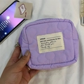 Detailed shot of purple quilted makeup bag with floral stitching and center cotton tag - Quilted Flower Purple