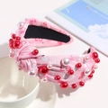Detail of pink knotted headband with love pattern, red pearls, and heart decorations - Pink LOVE