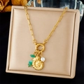 Close-up of a gold conch pendant necklace with green stones and a white pearl detail - Nautilus Shell With Green Beads And Pearl (N3477)