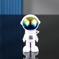 Statuetta di astronauta con visiera iridescente in tuta bianca su superficie riflettente - Testa Grande Sfumato