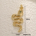 Macro shot of 30mm gold snake pendant with green gem eyes and sparkling zircons - A0203/S-Shape Snake / Gold