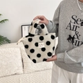 Dettaglio della borsa in peluche a pois con cerniera ed etichetta su tessuto morbido - Pois su sfondo bianco
