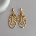 Macro shot of gold-plated triple-layered oval earrings with wavy textured finish - Gold