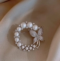 Detalle de broche de corona de perlas con mariposa de circón brillante sobre tela de seda - Plateado