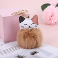 Close-up of a brown faux rabbit fur keychain with a calico cat head and gold metal clip - Camel