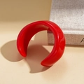 Macro shot of wide-band red resin bangle with glossy finish on minimalist display - Bright Red Open Cuff Bangle