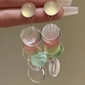 Detalle de los dijes de acrílico colorido y flecos dorados en pendientes largos de playa - Multicolor Blanco Amarillo Rosa