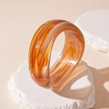 Nahaufnahme des klobigen Bernstein-Resin-Armreifs mit Marmortextur auf weißem Stein - Dunkelbraun