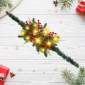 Detalle de guirnalda navideña con piñas, bayas rojas y luces LED cálidas - Estilo Piña