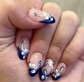Detail of almond press-on nails with blue French tips and white floral patterns - Dark Blue French Floral (AW439)