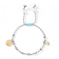 Detailed shot of multi-color woven cord bracelet with white pearls and gold religious medals - Multicolor