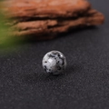 Single 16mm white granite natural stone bead with black spots on a textured background - Sesame Jasper