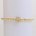 Close-up of golden beaded stretch bracelet with a micro-pave cubic zirconia letter H charm - Letter H